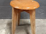 a small wooden stool sitting on a cement floor
