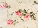a white sheet with pink roses on it on a bed