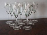 six wine glasses with flowers are lined up on a wooden table