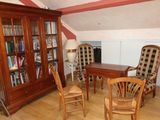 a room with a table, chairs, bookshelf, and a bookcase