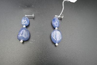 deux paires de boucles d'oreilles en perles de verre bleues et blanches sur un fond noir
