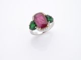 un gros plan d'une bague rose et verte posée sur une surface blanche