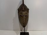 an image of a wooden mask on a stand on a white surface