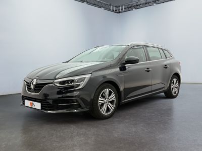 Une voiture grise est garée dans une pièce blanche au sol noir.