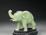 une petite statue d'éléphant verte posée sur un socle noir