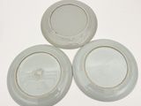 three white plates with gold rims sitting on a white surface