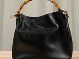 black leather handbag with bamboo handle on wooden table
