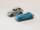 two toy cars sitting next to each other on a white surface