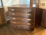 a wooden chest of drawers in the corner of a room