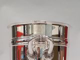 a silver vase with a handle on it on a table
