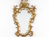 un miroir à dorures accroché au mur, à côté d'un mur blanc