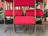 four red chairs sitting next to each other in front of a wall