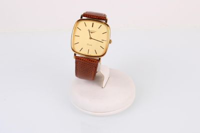 une photo d'une montre posée sur un support, sur une surface blanche