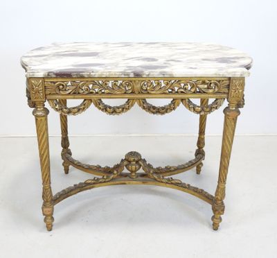 une table richement sculptée, dotée d'un plateau en marbre, posée sur un sol blanc