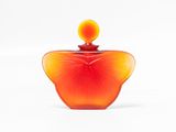an orange glass perfume bottle with a yellow top on a white surface
