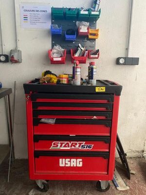 une armoire à outils rouge, sur laquelle sont posés des outils, dans un garage