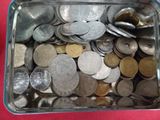 un récipient métallique rempli de pièces de monnaie posé sur une surface rouge