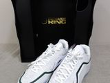 a pair of white and green sneakers in front of a black box