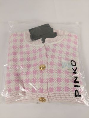 un pull rose et blanc dans un sac en plastique posé sur une surface blanche