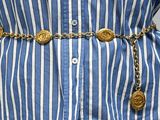 un gros plan sur la taille d'une femme portant un t-shirt rayé bleu et blanc, avec une ceinture dorée
