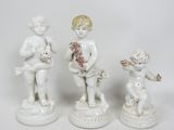 trois figurines blanches représentant des enfants, ornées de fleurs