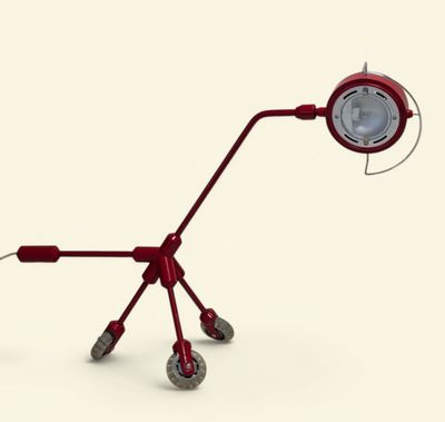 une lampe rouge posée sur des roulettes, sur une surface blanche