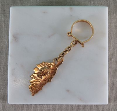 porte-clés plaqué or orné d'une breloque en forme de feuille, posé sur une surface en marbre
