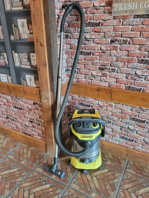 un aspirateur posé par terre devant un mur de briques