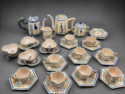 many cups and saucers and a teapot on the table