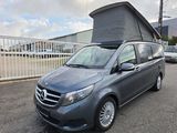 mercedes v - class camper van parked in a parking lot with a tent on top of it