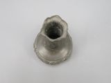 un petit vase en argent posé sur une surface blanche