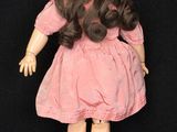a doll that is wearing a pink dress and hat
