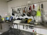 many pots and pans hanging on the wall above the sink