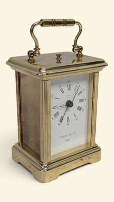 une petite horloge en laiton avec des chiffres romains