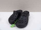 black crocs clogs with green string on white surface