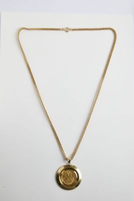 un collier en or avec une pièce de monnaie sur une chaîne