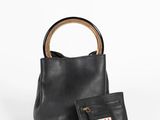 un sac à main noir muni d'une poignée en bois, à côté d'un porte-monnaie noir