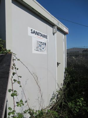 une cabane de toilettes blanche avec une pancarte sur le côté