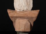 a white marble bust of a man with long hair on top of a wooden base