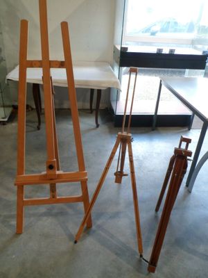 un chevalet en bois posé dans une pièce avec une table et des chaises