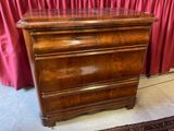 une commode en bois devant un rideau rouge