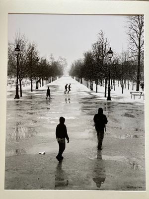black and white photograph of people walking down a snowy street