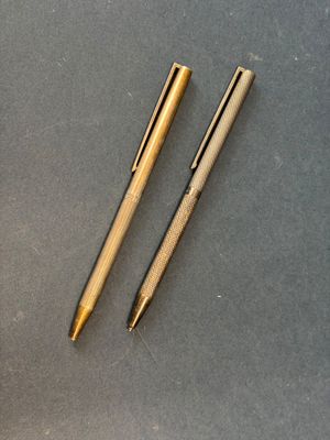 two pens and a ballpoint pen on a table