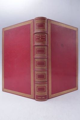 an old red book with gold trim sitting on top of a white surface