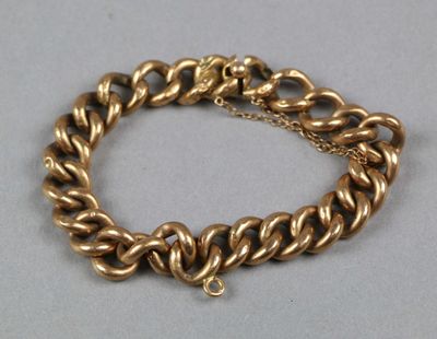 gros plan d'un bracelet en chaîne en or sur une surface grise