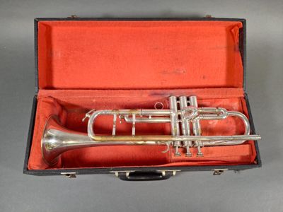 a silver trumpet in a red case on a gray surface