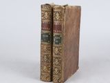 two old books sitting on top of each other on a white surface