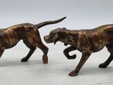 two bronze figurines of two dogs on a white surface
