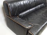 black leather sofa with gold piping on the arms and back