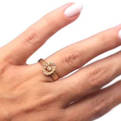 the woman ' s hand is holding a gold ring with a diamond center